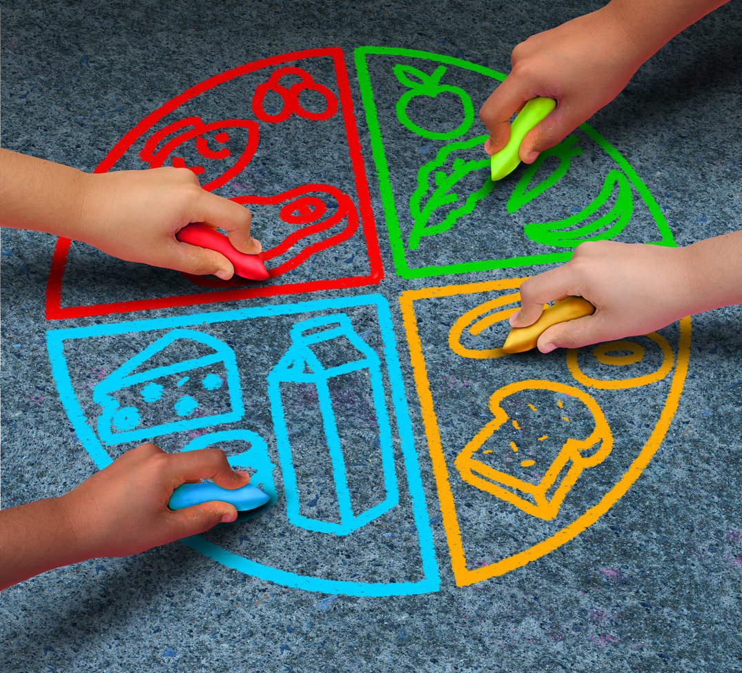 Food groups nutrition and healthy lifestyle concept as a group of diverse children holding chalk drawing a pie chart diagram on asphalt with protein dairy fruits and vegetables and starch symbols.