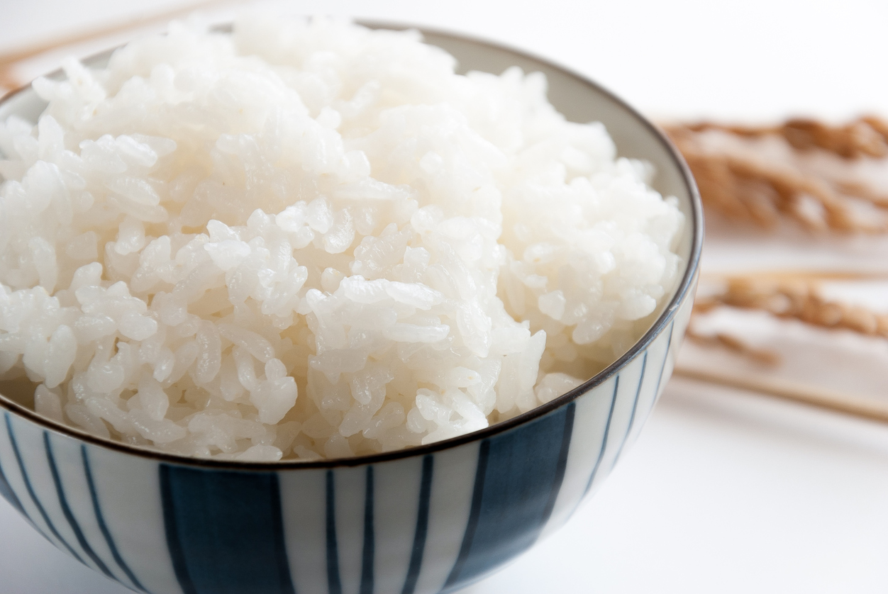 boild white rice served in bowl with rice stalks in white background