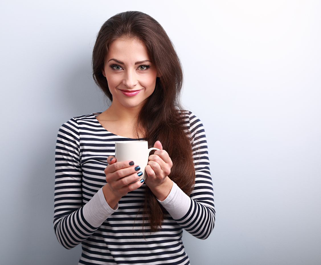 Cute young casual woman holding in hand cup of tea
