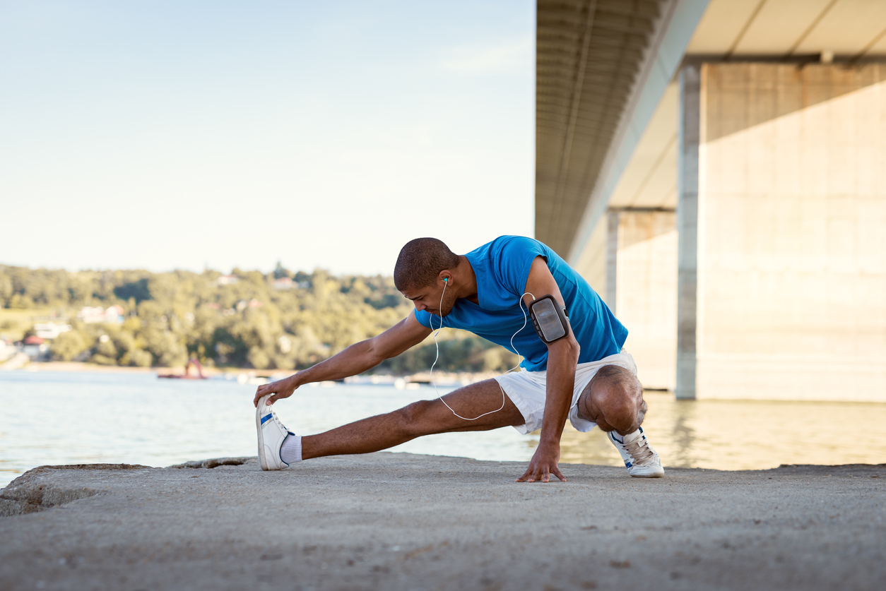 Young male athlete streching next to the river after morning work out.