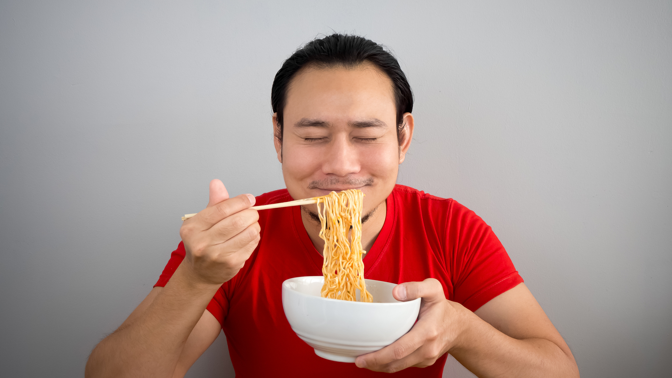 Asian man eating instant noodles.