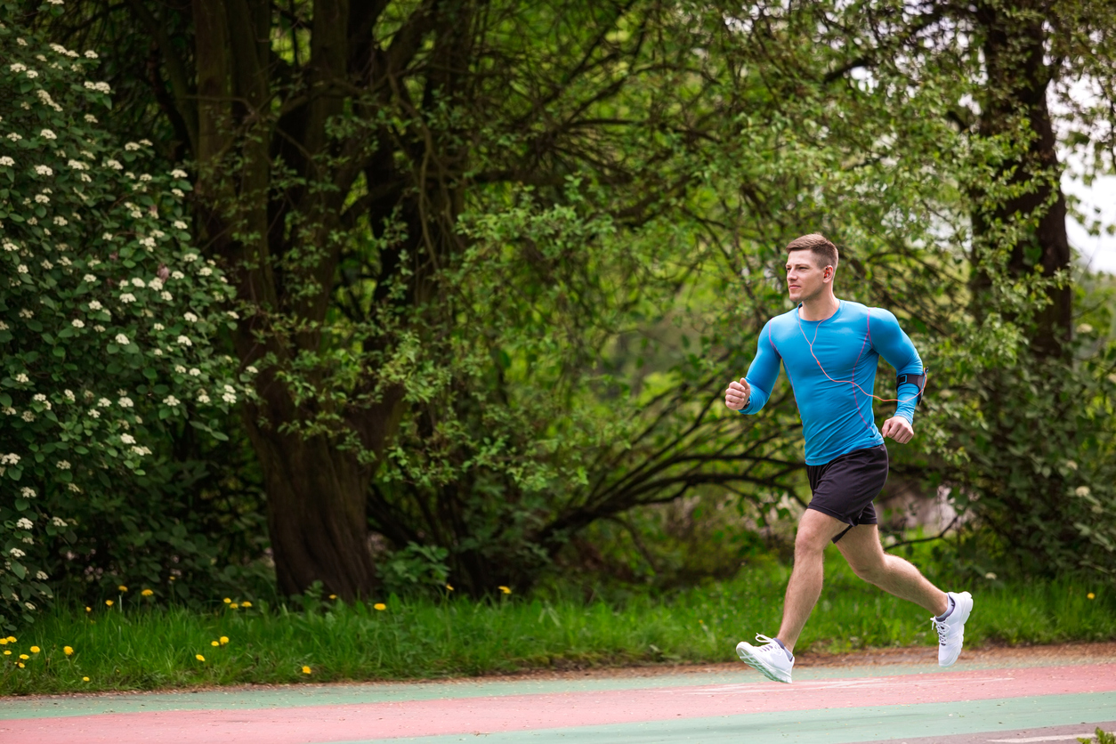 A photo of young, muscular man jogging fast.