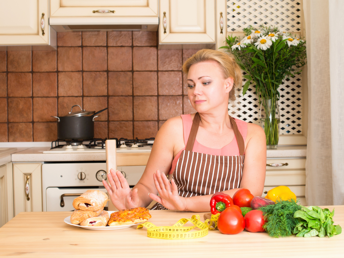 Healthy and junk food concept. Housewife woman with vegetables rejecting hamburger and pizza. Diet. Weight loss.