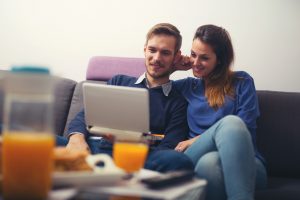 Happy young couple using a laptop at home and smiling