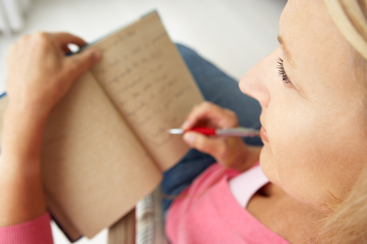 Senior woman writing in notebook at home