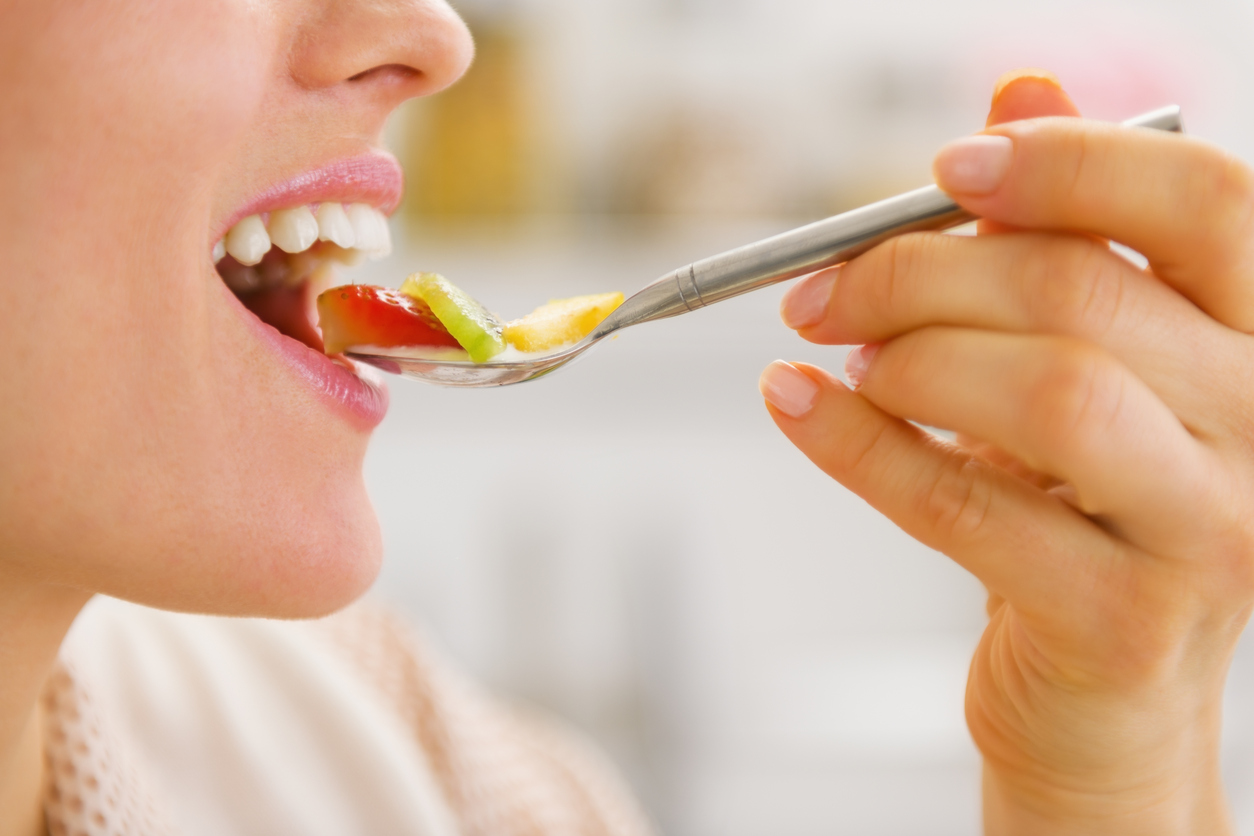 Closeup on woman eating fruits on spoon