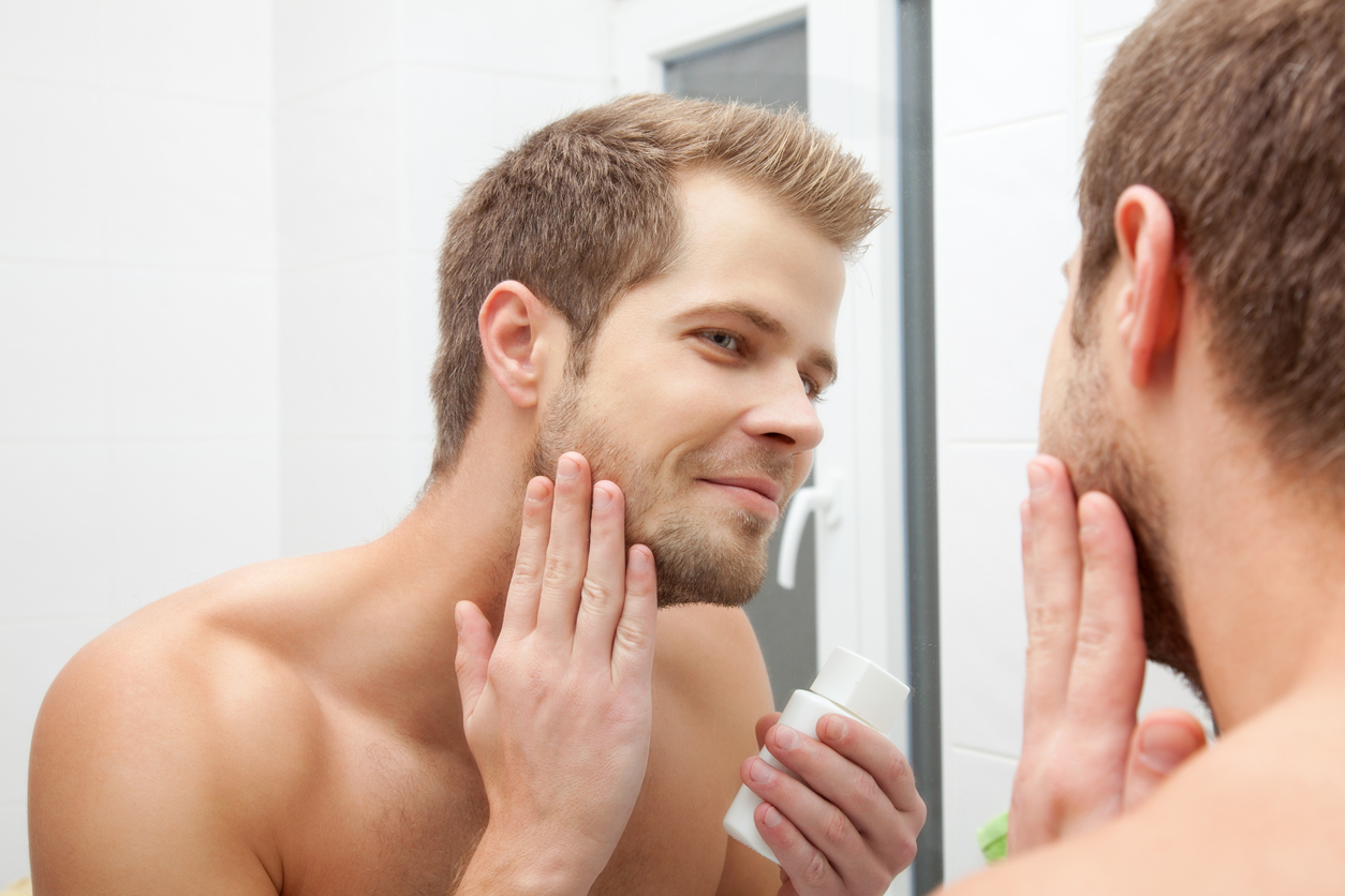 Man looking into the mirror and applying aftershave