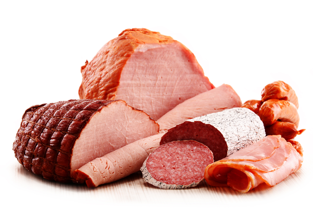 Assorted meatworks products including ham and sausages isolated on white