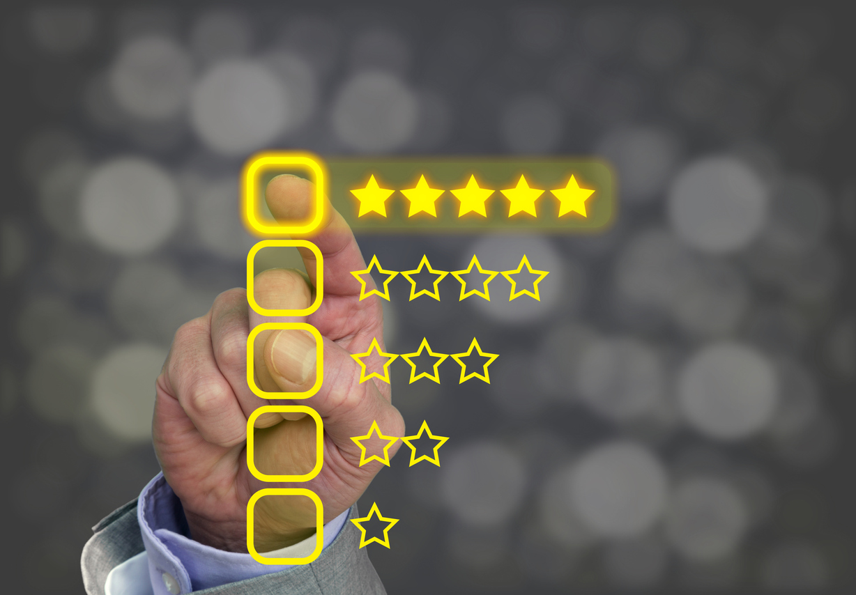 Hand pressing yellow five star button of performance rating on dark background with bokeh
