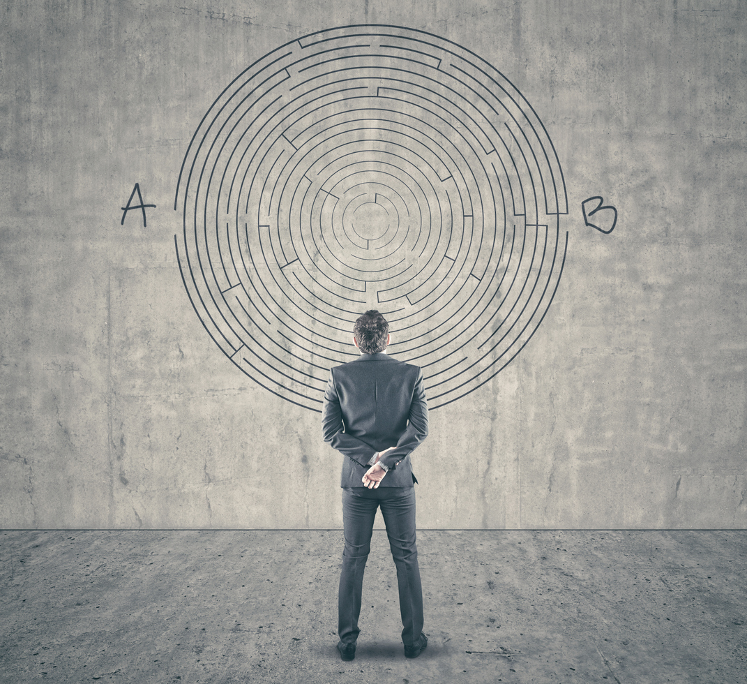 Business concept. Back view of businessman looking at a maze on wall