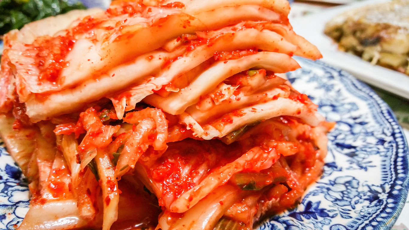 Korean kimchi slices stacked on a plate. This is a traditional Korean staple made from fermented cabbages, together with hot chilli and other spices.
