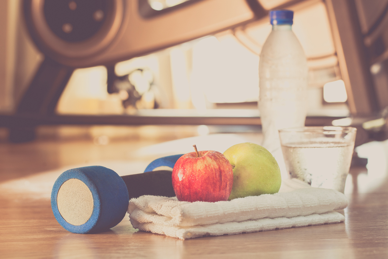 Fitness background with bottle of water, dumbbells and apple