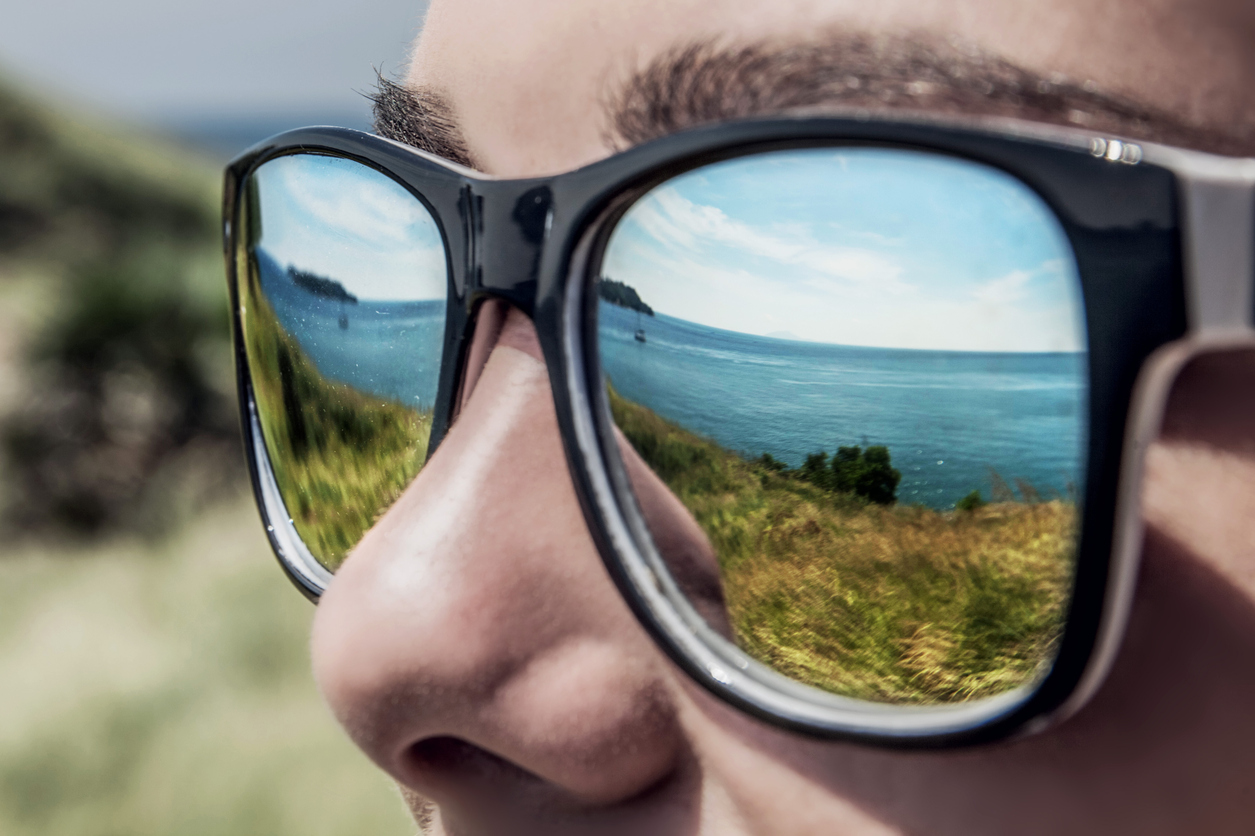 Sea reflected in man's sunglasses